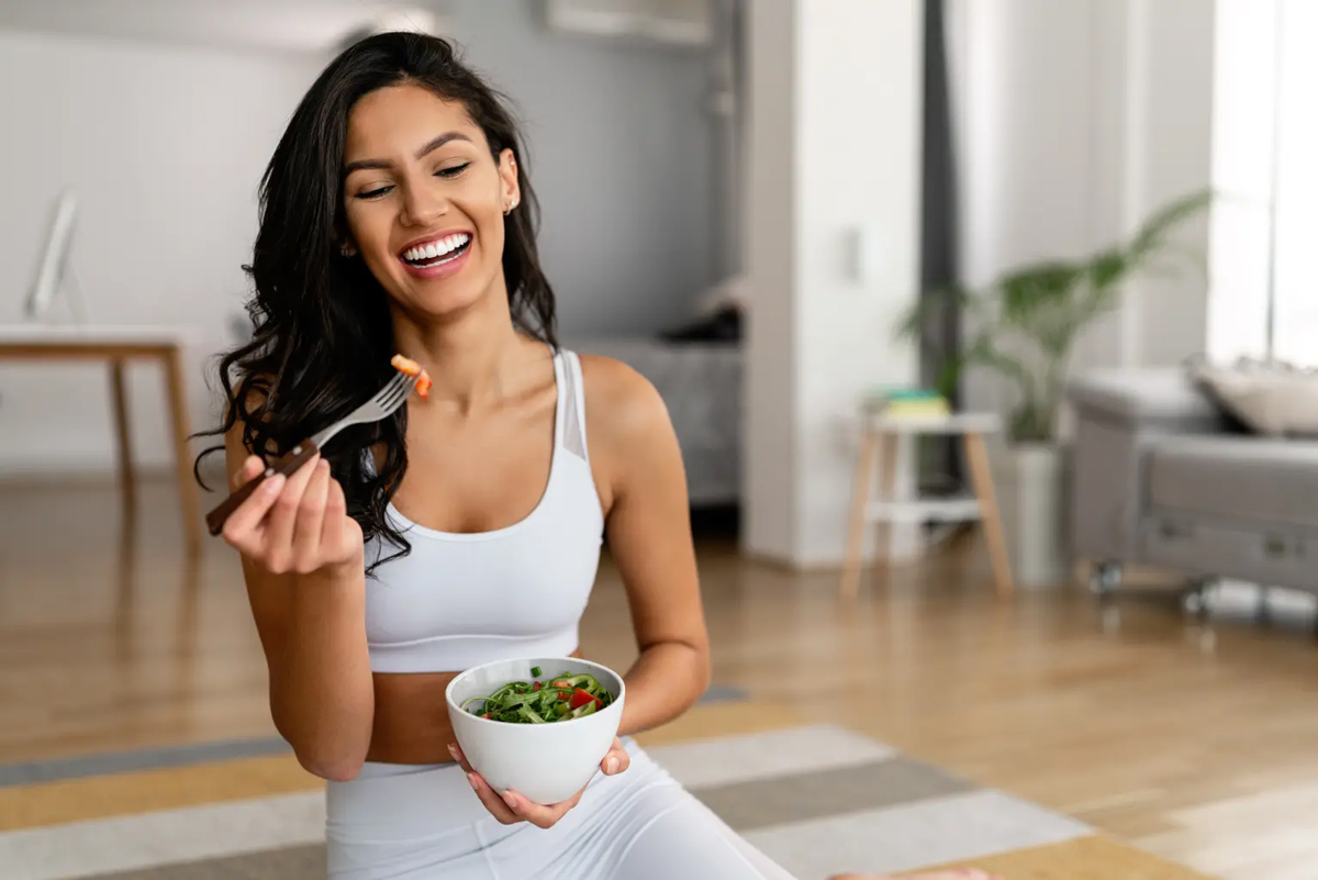 Woman enjoying a fresh salad with balanced ingredients, part of a conversation around are seed oils bad for you and balanced eating