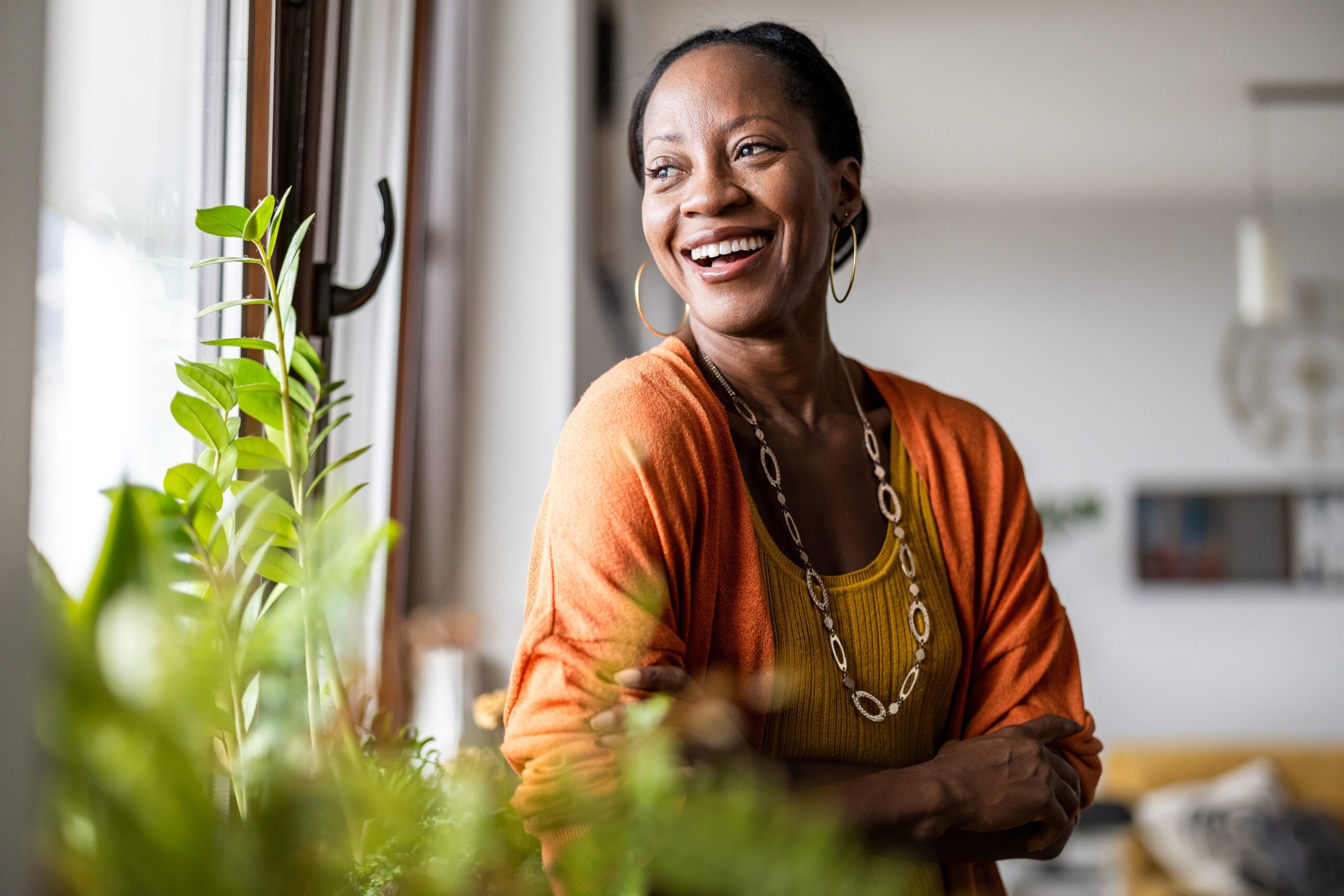 Middle-aged woman looking out the window and smiling. Menopause Series.